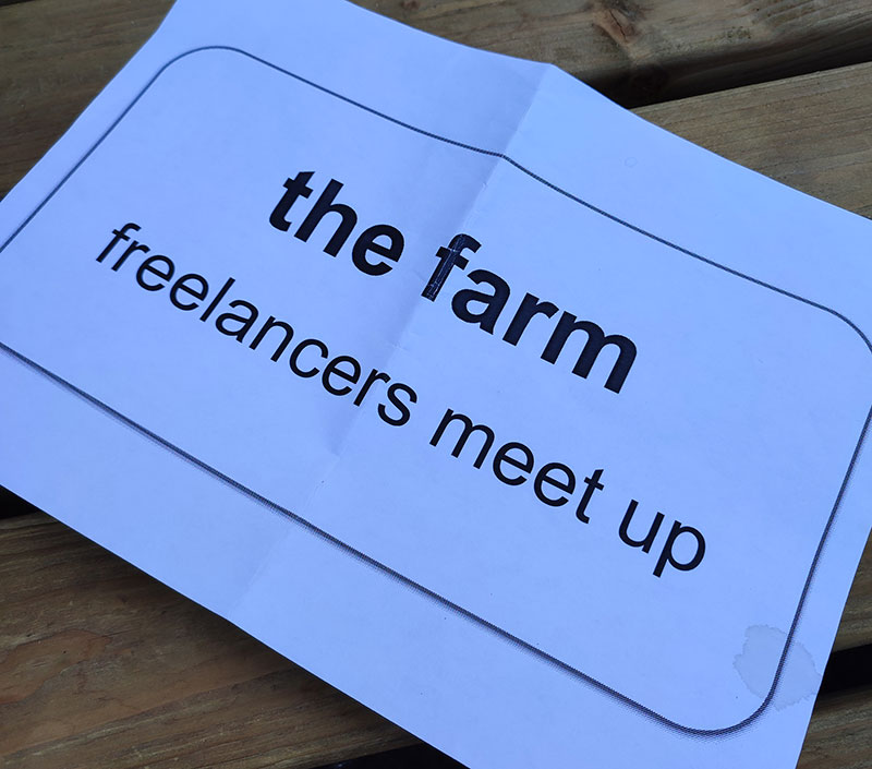 A printed sign on a white A4 sheet reading the Farm freelancers meet up